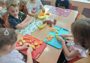 Dzieci pracujące przy stole nad szaszłykami.