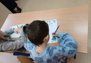 Chłopiec wypisujący listę życzeń do Mikołaja.