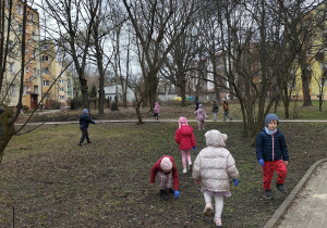 dzieci zbierają smieci koło bloków