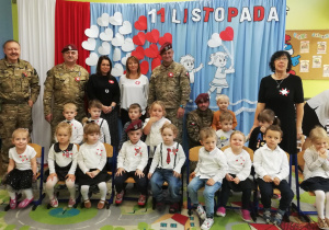 Dzieci z grupy pierwszej wraz nauczycielami, przedstawicielem z biblioteki i żołnierzami pozują do zdjęcia grupowego.