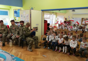 Dzieci z grupy pierwszej i trzeciej wraz z żołnierzami oglądają występ innych dzieci.