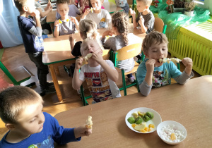 dzieci jedzą owocowe szaszłyki