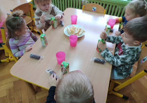 Dzieci spożywają słodki poczęstunek.