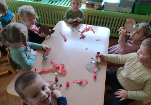 Dzieci naklejają kolce z bibuły na papierowy kształt jeża.
