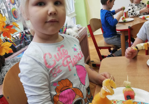 Dziewczynka trzyma swojego owocowego szszłyka.