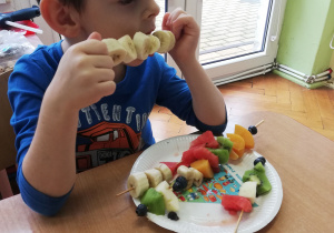 Chłopiec je owoce z szaszłyka.