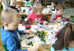 dzieci przygotowują kwiaty do umieszczenia w bukiecie