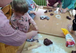Dzieci wałkują ciasto piernikowe.
