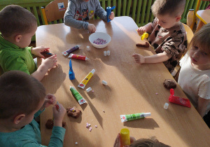Dzieci dekorują kolorowym lukrem upieczone pierniczki.