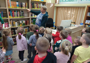 Pani bibliotekarka pokazuje księgozbiór lektur.