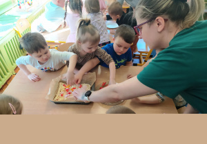 Dzieci nakładają składniki na ciasto.
