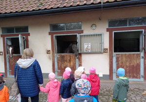 Oglądanie koni w boksach przez dzieci.