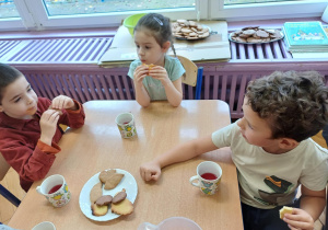 Troje dzieci degustujące ciastka po obiedzie.