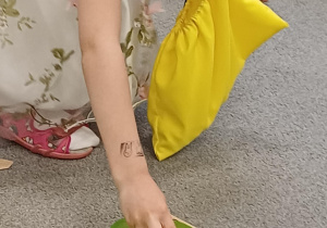Dziewczynka wkłada koral symbolizujący rok do miseczki w kolorze wiosny.