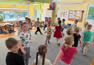 Dzieci tańczą w kole przy piosenkach dziecięcych.