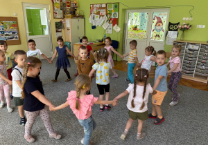 Dzieci tańczą w kole przy piosenkach dziecięcych.