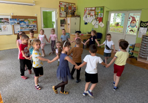 Dzieci tańczą w kole przy piosenkach dziecięcych.