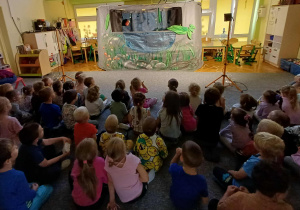Grupa dzieci siedząca przed sceną "nad stawem".