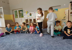 Jedno dziecko robiące miejsce drugiemu przekazując świecę.