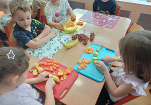 Dzieci pracujące przy stole nad szaszłykami.