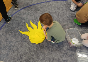 Chłopiec składający słoneczko urodzinowe.