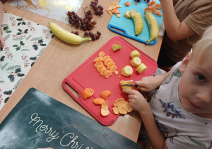 Chłopiec krojący banana nożem na plastry.