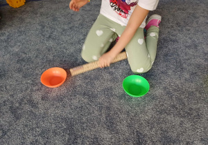 Dziecko odmierza odległości między miseczkami, przed przystąpieniem do wykonywania zadania.