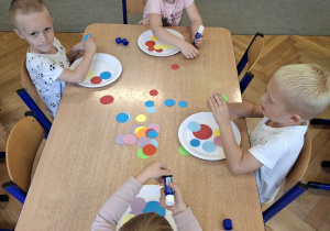 Dzieci wykonujące pracę plastyczną.