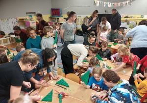 Zdjęcie grupy ludzi pracujących nad wykonaniem choinek.