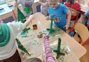 Dzieci malujące choinki na zielono.