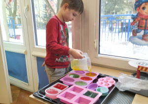 Chłopiec wylewa mydło do formy