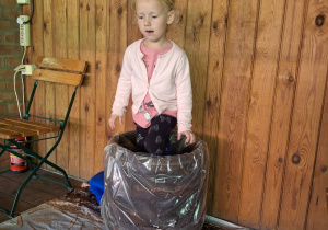 Dziewczynka depcze kapustę w drewniane beczce.