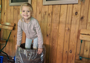 Dziewczynka depcze kapustę w drewniane beczce.