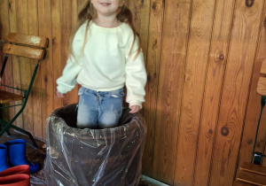 Dziewczynka depcze kapustę w drewniane beczce.