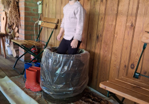 Dziewczynka depcze kapustę w drewniane beczce.