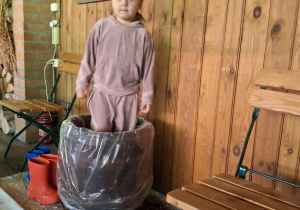 Dziewczynka depcze kapustę w drewniane beczce.