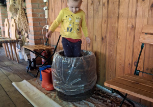 Chłopiec depcze kapustę w drewniane beczce.