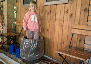 Dziewczynka depcze kapustę w drewniane beczce.