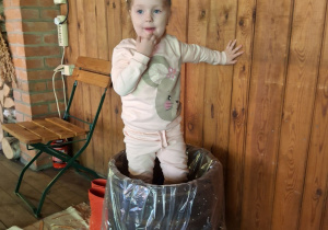 Dziewczynka depcze kapustę w drewniane beczce.