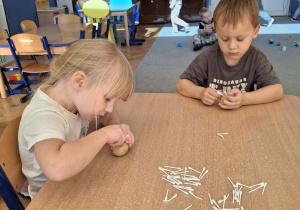 Dziewczynka i chłopiec wykonujący pracę plastyczną.