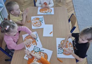 Wyklejanie plasteliną kropek na obrazku przedstawiającym dynię.