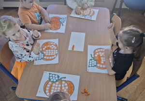 Wyklejanie plasteliną kropek na obrazku przedstawiającym dynię.