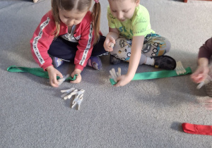 Dzieci przypinają klamerki na szarfę.