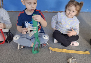 Dzieci przypinają klamerki na szarfę.