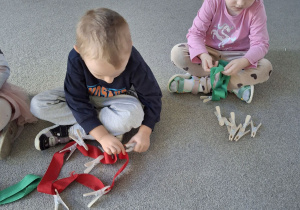 Dzieci przypinają klamerki na szarfę.