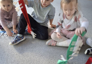 Dzieci przypinają klamerki na szarfę.