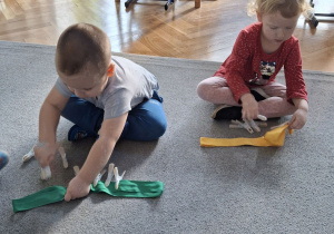 Dzieci przypinają klamerki na szarfę.