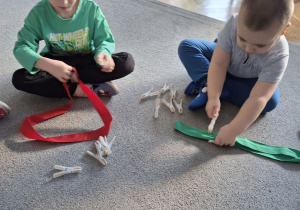 Dzieci przypinają klamerki na szarfę.