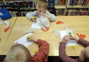 Dzieci przyklejające na kartkę elementy plastyczne.