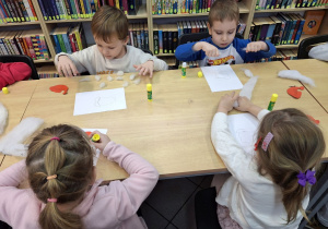 Dzieci przyklejające na kartkę elementy plastyczne.